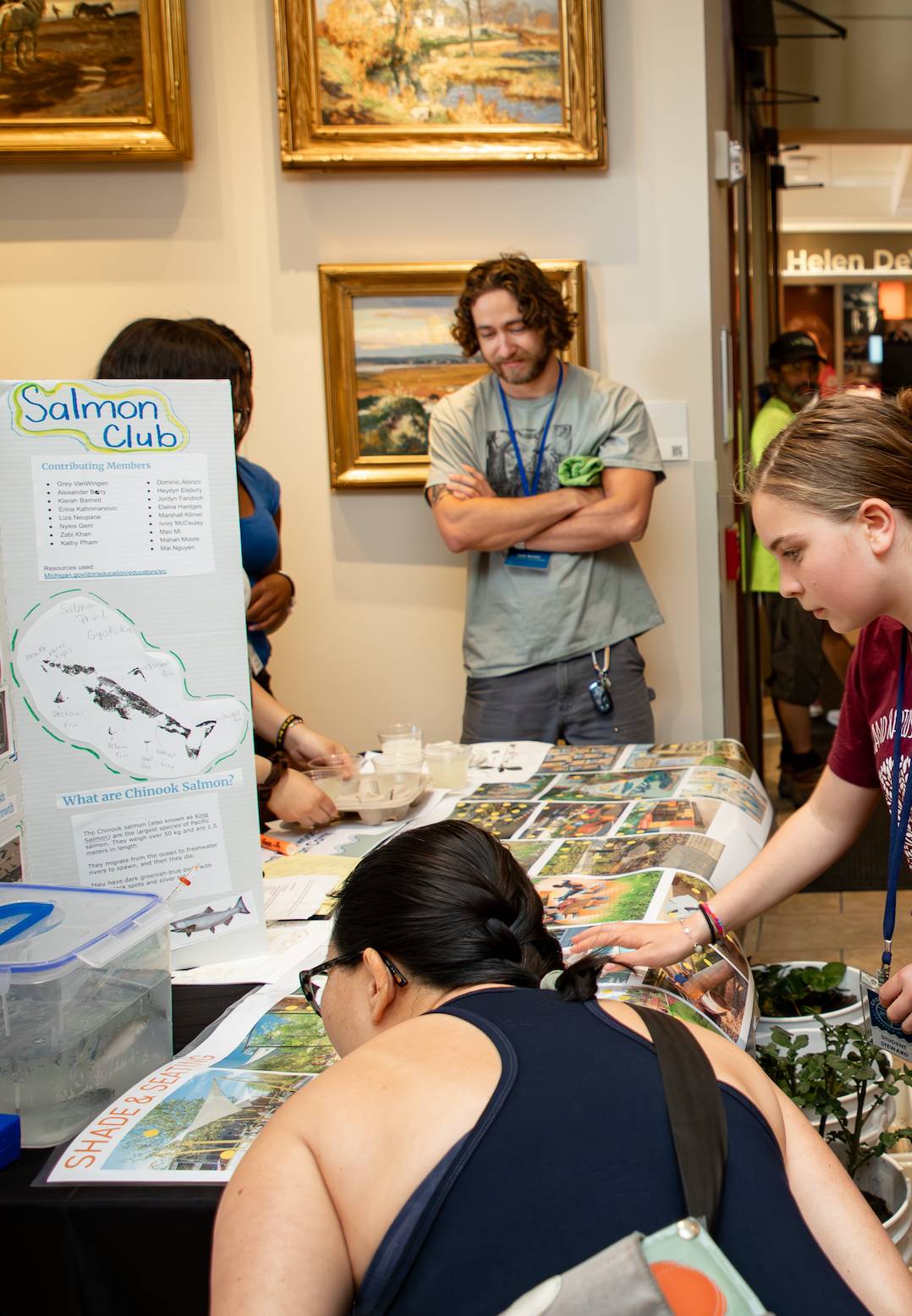 kids and adults standing around a trifold that reads "salmon" indoors